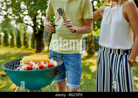 Coppia giovane avente un barbecue in giardino Foto Stock