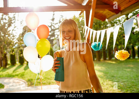 Donna felice di mangiare un hot dog su un party in giardino Foto Stock