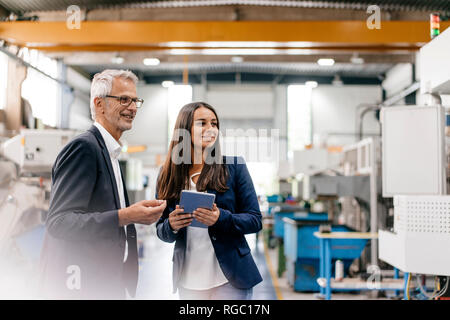 Proprietario di una donna in high tech enterprise, avente un incontro in officina in fabbrica Foto Stock