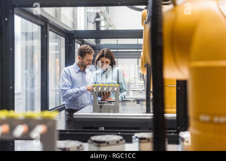 I colleghi di high tech azienda il controllo di robot industriali, con tavoletta digitale Foto Stock