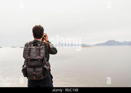 Giovane uomo a scattare foto di un lago in Isola Vesteralen, Lapponia, Norvegia Foto Stock