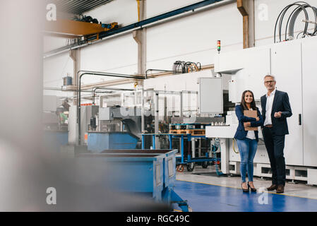 Proprietario di una donna in high tech enterprise, avente un incontro in officina in fabbrica Foto Stock