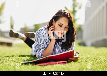 Ritratto di studente giacente sul prato leggendo le sue note Foto Stock