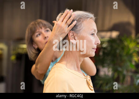 Donna aiutando senior donna con i capelli in un negozio Foto Stock