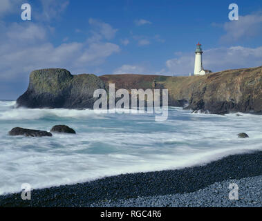 Stati Uniti d'America, Oregon, Yaquina Capo Eccezionale area naturale, Yaquina Capo Faro si affaccia turbolento di surf e la spiaggia rocciosa. Foto Stock