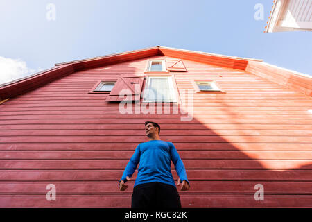 Basso angolo vista di atleta in piedi di fronte a casa rossa Foto Stock