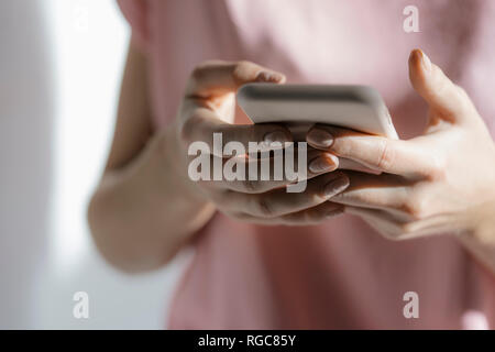 Le mani della giovane donna alla messaggistica di testo, close-up Foto Stock