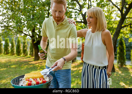 Coppia giovane avente un barbecue in giardino Foto Stock