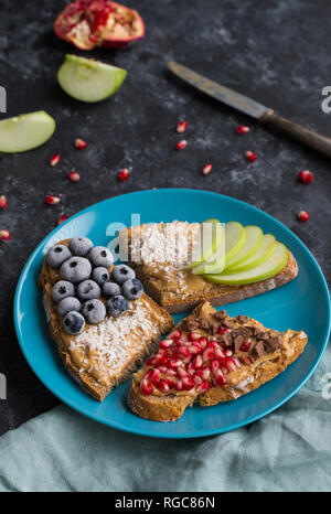 Fette di pane con vari ingredienti sulla piastra Foto Stock