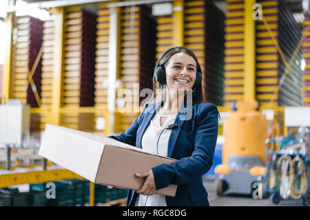 Giovane donna che lavorano presso il servizio pacchi, portando i pacchi in magazzino Foto Stock