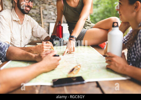 Gruppo di escursionisti seduti insieme la pianificazione di un percorso escursionistico guardando alla mappa Foto Stock