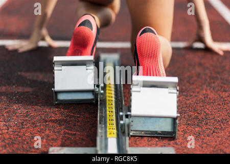 Runner Teenage inginocchiato sul blocco di partenza, close up Foto Stock