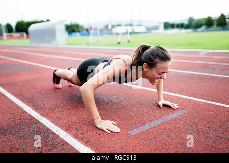 Teenage runner facendo spingere ups sulla pista Foto Stock