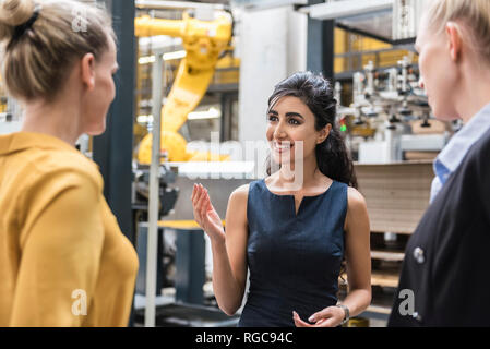 Ritratto di donna sorridente a parlare con i colleghi nel moderno stabilimento Foto Stock