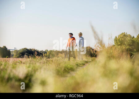 Due vecchi amici facendo una passeggiata attraverso i campi, parlando di vecchi tempi Foto Stock