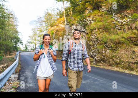 L'Italia, Massa, sorridente coppia giovane camminando sulla strada asfaltata in Alpi Apuane montagne Foto Stock