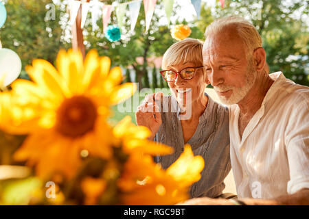 Felice coppia senior abbracciando in un party in giardino Foto Stock