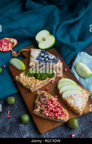 Fette di pane con vari ingredienti sulla tavola di legno Foto Stock