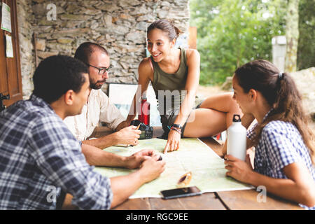 Gruppo di escursionisti seduti insieme la pianificazione di un percorso escursionistico guardando alla mappa Foto Stock