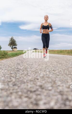 Donna matura in esecuzione in remoto paese lane in estate Foto Stock