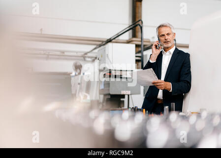 Manager di parlare al telefono in high tech company Foto Stock