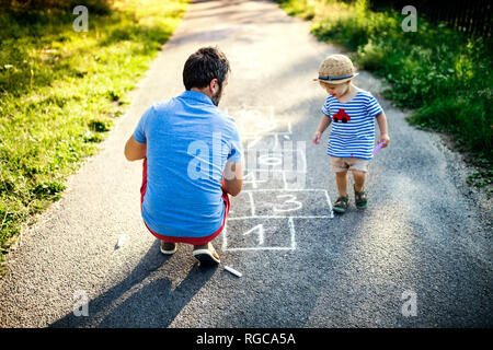 Padre giocando campana insieme con il suo piccolo figlio Foto Stock