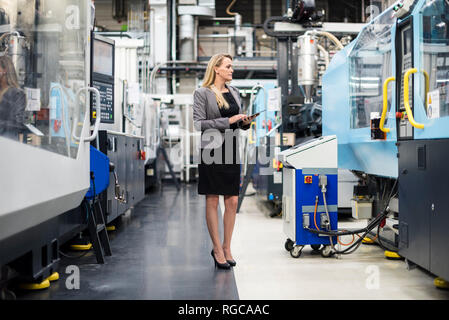 Donna che utilizza tablet a macchina in fabbrica e negozio Foto Stock