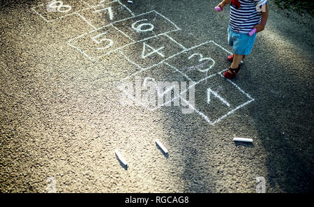 Bambina con tratte campana sulla strada, vista parziale Foto Stock