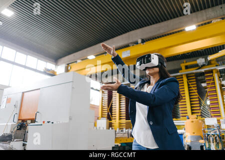 Giovane donna che lavorano nel magazzino di distribuzione, indossando occhiali VR Foto Stock