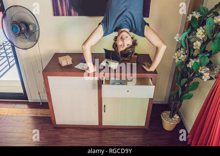 Un uomo si erge sulle sue mani capovolto nel soggiorno Foto Stock
