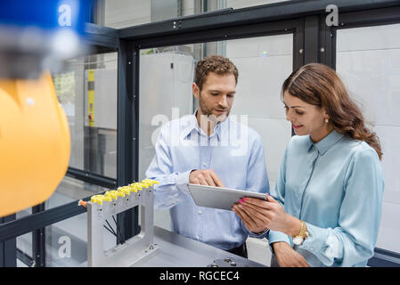 I colleghi di high tech impresa in grado di controllare le macchine di fabbricazione, utilizzando tavoletta digitale Foto Stock