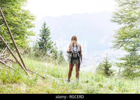 In Germania, in Baviera, Oberammergau, giovane donna escursionismo in piedi sul prato di montagna Foto Stock