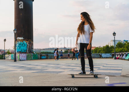 Giovane donna cavallo skateboard in città Foto Stock