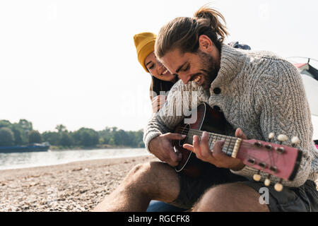Felice coppia giovane con la chitarra al Riverside Foto Stock