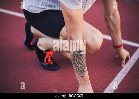 Runner sulla pista di tartan in posizione di partenza Foto Stock