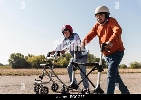 Due vecchi amici che indossa caschi di sicurezza, gareggiando in una carrellata di gara dello scuotipaglia Foto Stock