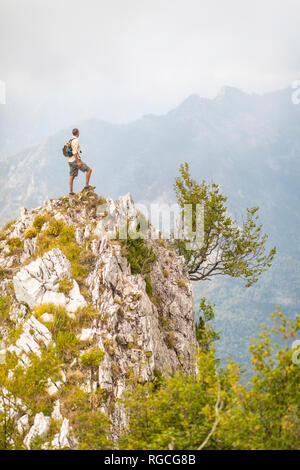 L'Italia, Massa, uomo in piedi sulla sommità di un picco nelle Alpi Apuane montagne Foto Stock