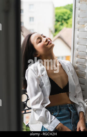Sorridente attraente giovane donna seduta alla finestra Foto Stock