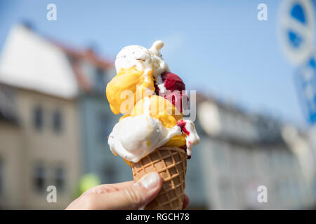 Mano azienda cono gelato con vari tipi di gelati, close-up Foto Stock