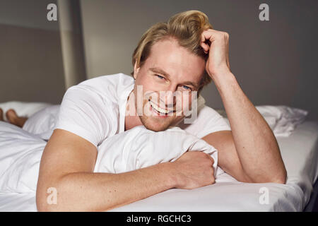 Ritratto di ridere giovane uomo disteso sul letto Foto Stock