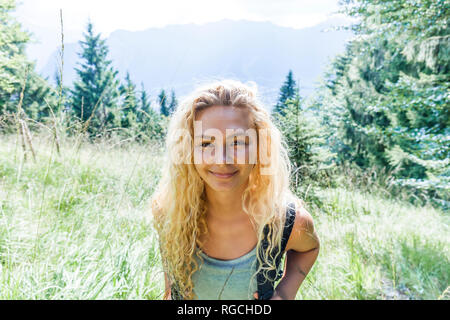 In Germania, in Baviera, Oberammergau, ritratto di sorridere giovane donna escursionismo sul prato di montagna Foto Stock