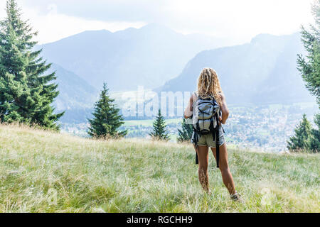 In Germania, in Baviera, Oberammergau, giovane donna escursionismo in piedi sul prato di montagna Foto Stock