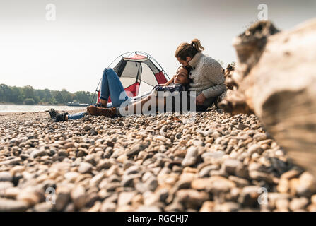 Felice coppia giovane rilassante di una tenda al Riverside Foto Stock