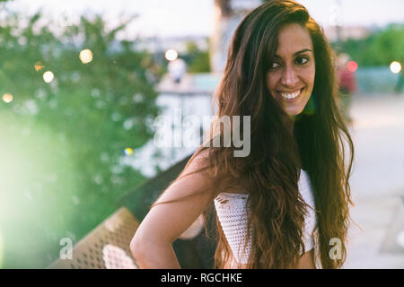 Ritratto di bella sorridente giovane donna con capelli lunghi marrone all'aperto Foto Stock