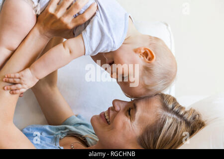 Felice madre cuddling con la sua bambina sul lettino Foto Stock