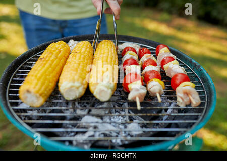 Pannocchia e spiedini di carne sul grill al barbecue nel giardino Foto Stock