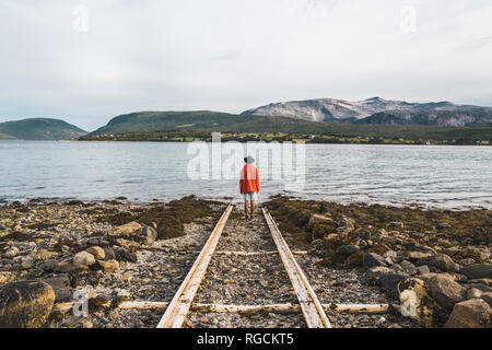 Norvegia settentrionale, uomo in piedi da sola a fiordo, guardando a vista Foto Stock