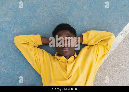 Giovane uomo nero dormire sul pavimento con le mani dietro la testa Foto Stock