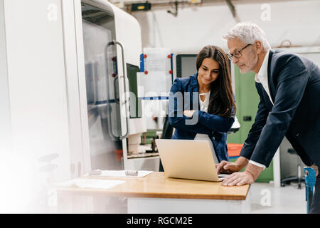 Proprietario di una donna in high tech enterprise, avente una riunione utilizzando laptop Foto Stock