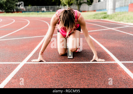 Teenage Runner in posizione iniziale sulla pista Foto Stock